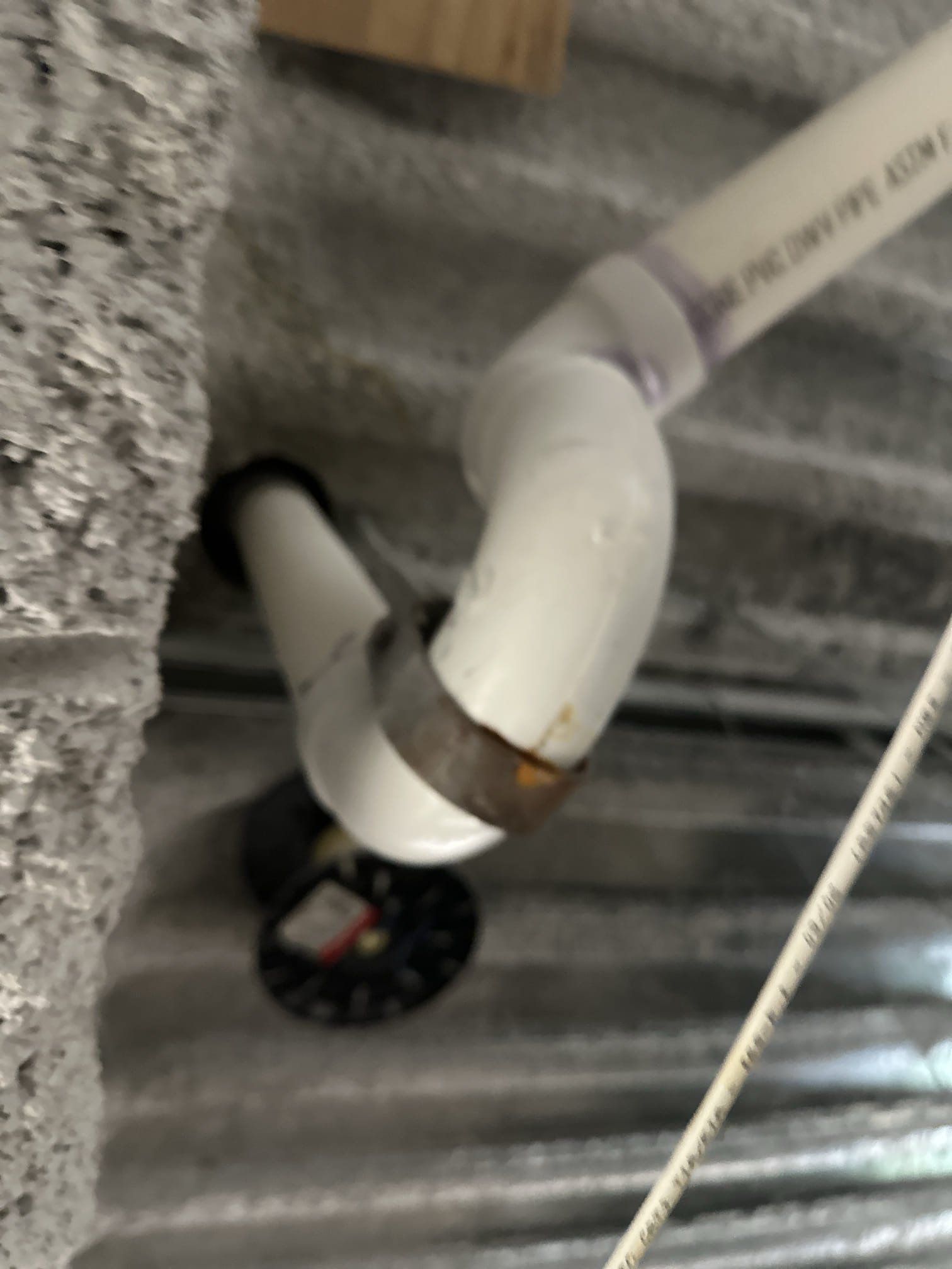 Upon arrival, I coordinated with the spa's front desk and proceeded to the physical therapy area to investigate a ceiling leak. I identified visible rust on the shower drain hanger and observed water dripping from the 1-inch PVC condensation drain directly above the affected ceiling spot. After running water in the shower for 20 minutes with no visible leaks, I discovered that the drain was sagging, causing water to accumulate and condense on the pipe, leading to the leak. I secured the drain to ensure proper drainage, which should prevent further condensation and dripping into the ceiling tile.