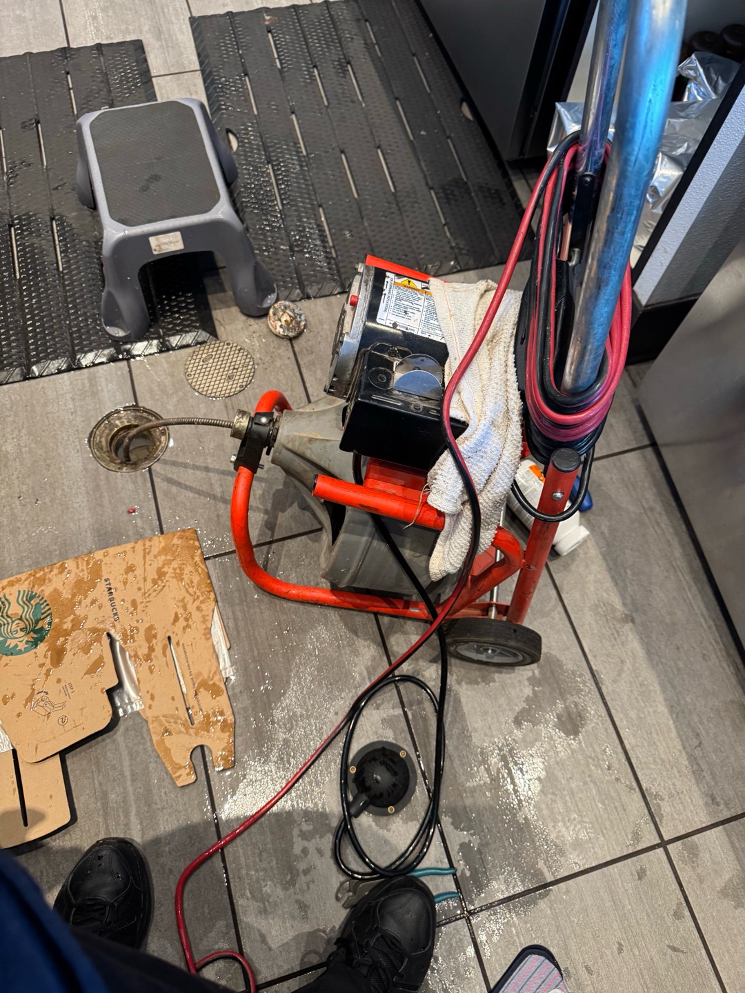 Upon arrival, I assessed the drains and noticed slow flow. I began by flooding the drains with hot water. Upon inspection, I found olive oil in the floor sinks. I opened the grease trap lid and observed the flow, then opened the clean-out at the front counter. I added cleaner and flushed with hot water, followed by running my medium machine down the line to remove clogs. I continued pouring five-gallon buckets of hot water until achieving a clear flow outside the grease trap baffle. I also flushed the floor sinks with hot water to remove grime. The drains are now flowing well, but a professional jetting is recommended.