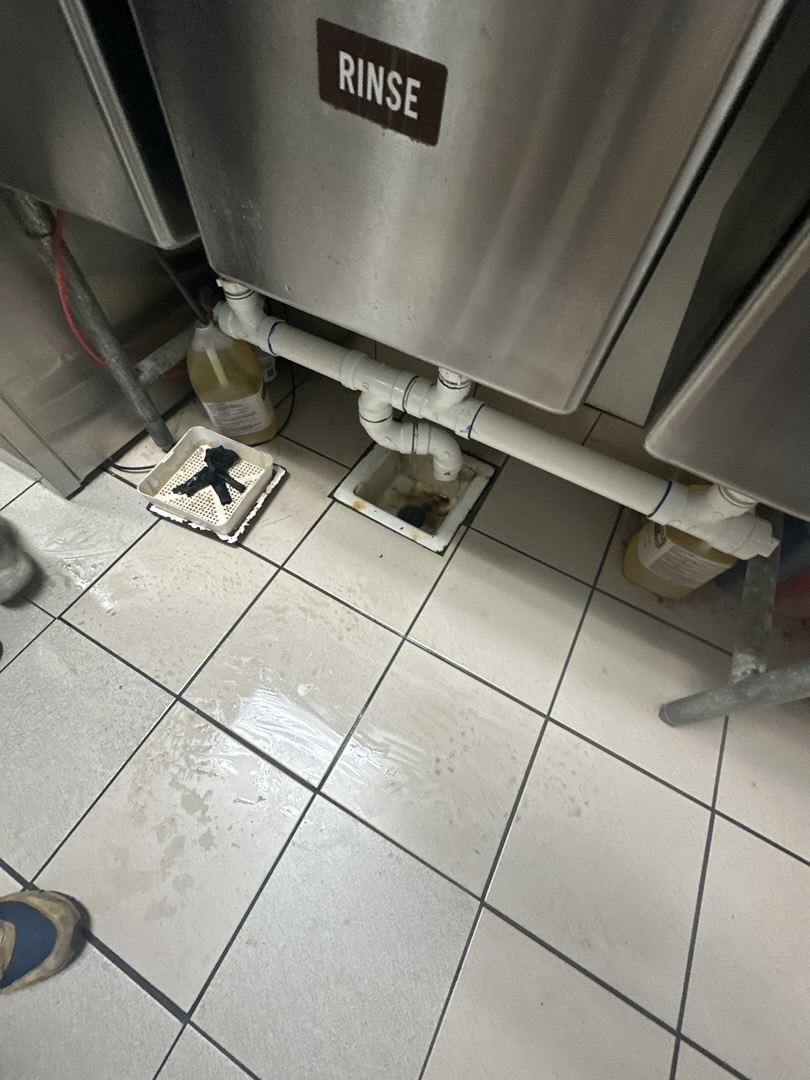 Upon inspection, the floor sink drain under the three-compartment sink exhibited a soft clog, causing overflow when attempting to empty the sink. I employed an auger to dislodge the accumulated grime within the drain. Following this, I flushed the drain with hot water for several minutes to ensure thorough cleaning. After confirming the drain's functionality, I filled the three-compartment sink with water and successfully dumped it, verifying that the floor sink now drains properly.