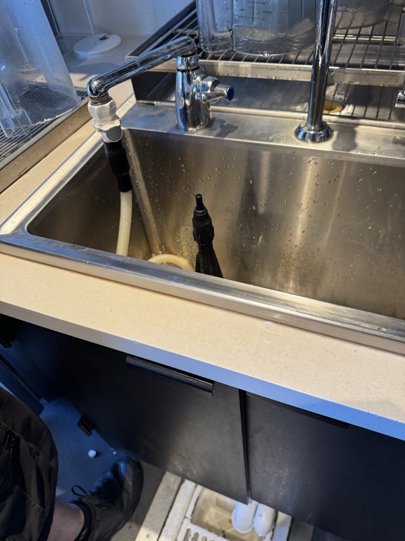 Upon inspection, it was determined that the cold bar sink had a missing section of caulking, causing water to leak into the cabinet below. The sink and countertop were noticeably wet, making it impossible to seal the area immediately. To address this, I applied a small tube of silicone to the affected corner of the sink. This temporary measure will prevent further water leakage until Tommy, who works the night shift, can seal the entire area at closing. He plans to ensure the countertop is dry and ready for a proper seal in the morning. Additionally, Tommy mentioned that he might take care of other tasks during his shift since the area will be dry and accessible.