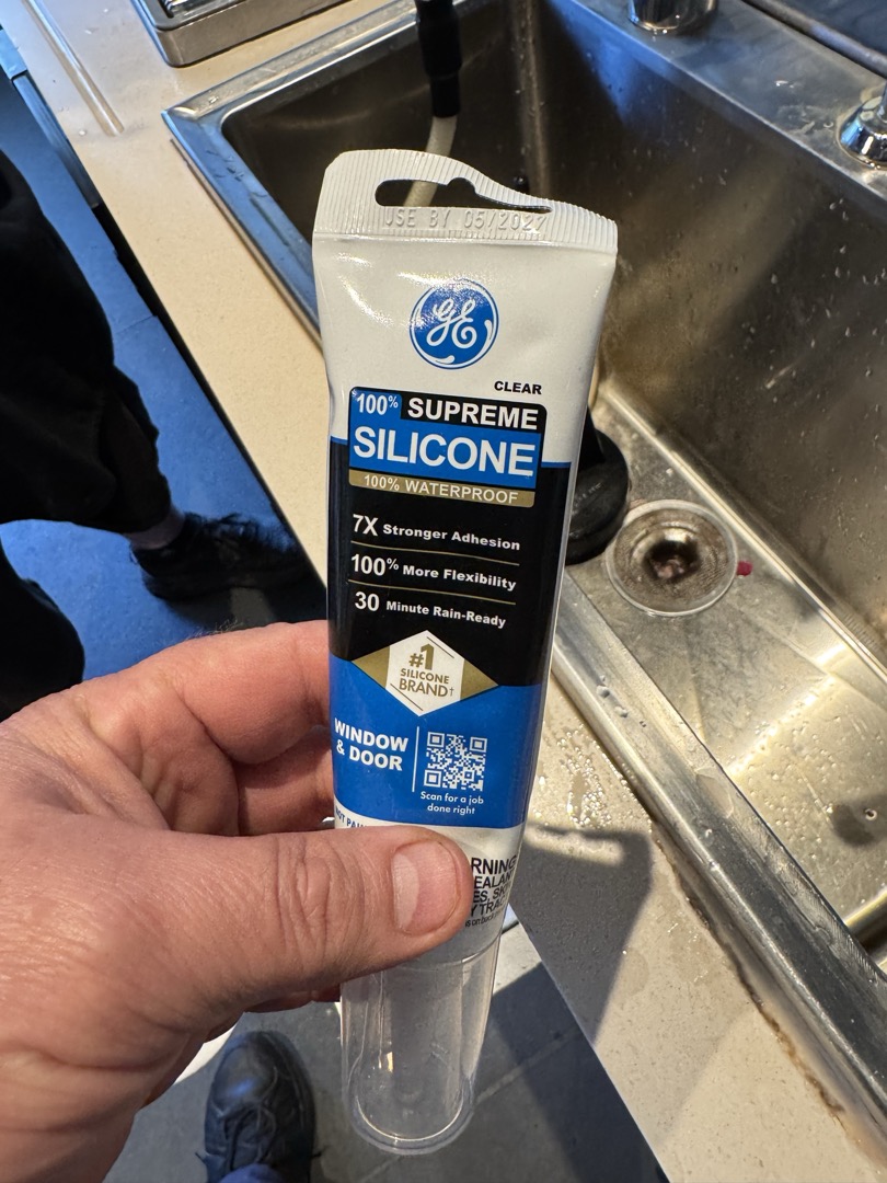 Upon inspection, it was determined that the cold bar sink had a missing section of caulking, causing water to leak into the cabinet below. The sink and countertop were noticeably wet, making it impossible to seal the area immediately. To address this, I applied a small tube of silicone to the affected corner of the sink. This temporary measure will prevent further water leakage until Tommy, who works the night shift, can seal the entire area at closing. He plans to ensure the countertop is dry and ready for a proper seal in the morning. Additionally, Tommy mentioned that he might take care of other tasks during his shift since the area will be dry and accessible.