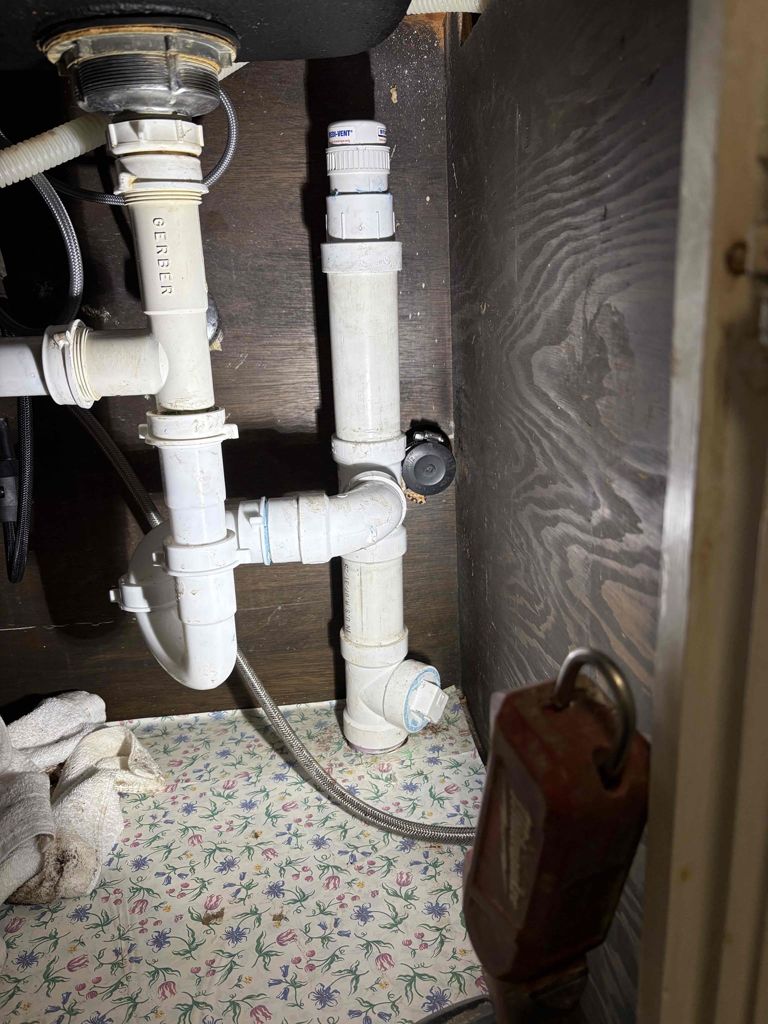 Client called us out today due to there being a leak that shows up on kitchen floor when kitchen fixtures were used. The waste arm in the wall was cast iron and copper and rest of home is still cast iron drains. Instead of pulling dishwasher and cutting the wall open, we left the old drain line abandoned in the wall, then drilled new 2” hole through bottom of cabinet and fed new 2” drain pipe through. Added new tee and studor vent up top, and below we cut out the few cast iron fittings right below the kitchen, and reconnected with new pvc properly supported and pitched. Once all connections were made, we tested our work with no issues. 

The old cast iron pipe was full of cast sludge, which will eventually start to cause issues in the home. Recommend jetting the line, and worst case replacing the line with pvc. 

1 yr warranty