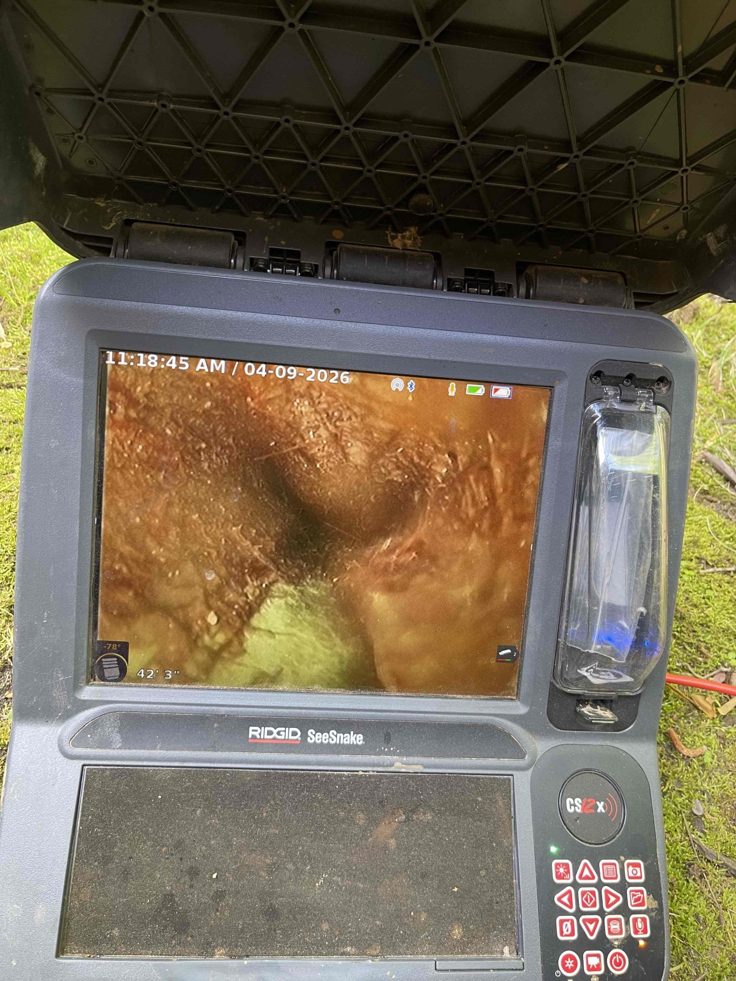 No issue with work of previous technician. Water/sewage coming up from base of the toilet. We pulled the toilet and ran the sewer camera. No issue with the drain under the home or in the customers yard. Sewer line runs off the property back into the woods. There is a 6” city cleanout to the left of the customers fence. There are two breaks in the line with root intrusions. One break is at the sanitary tee on the side of the cleanout stack with roots getting in, second break is 12-13’ deep at the bottom of the cleanout. There is visible sign in the cleanout up by the cap that the line was backing up and depositing sewage debris along the sides of the pipe which indicates there was a back up. Sewer is not currently backing up, but will continue to occur unless root intrusion is addressed. Notified homeowner to contact the city/county water department first to see if this cleanout is their responsibility. If it is not the sewer line will have to be jetted for a temporary fix, or dug up an