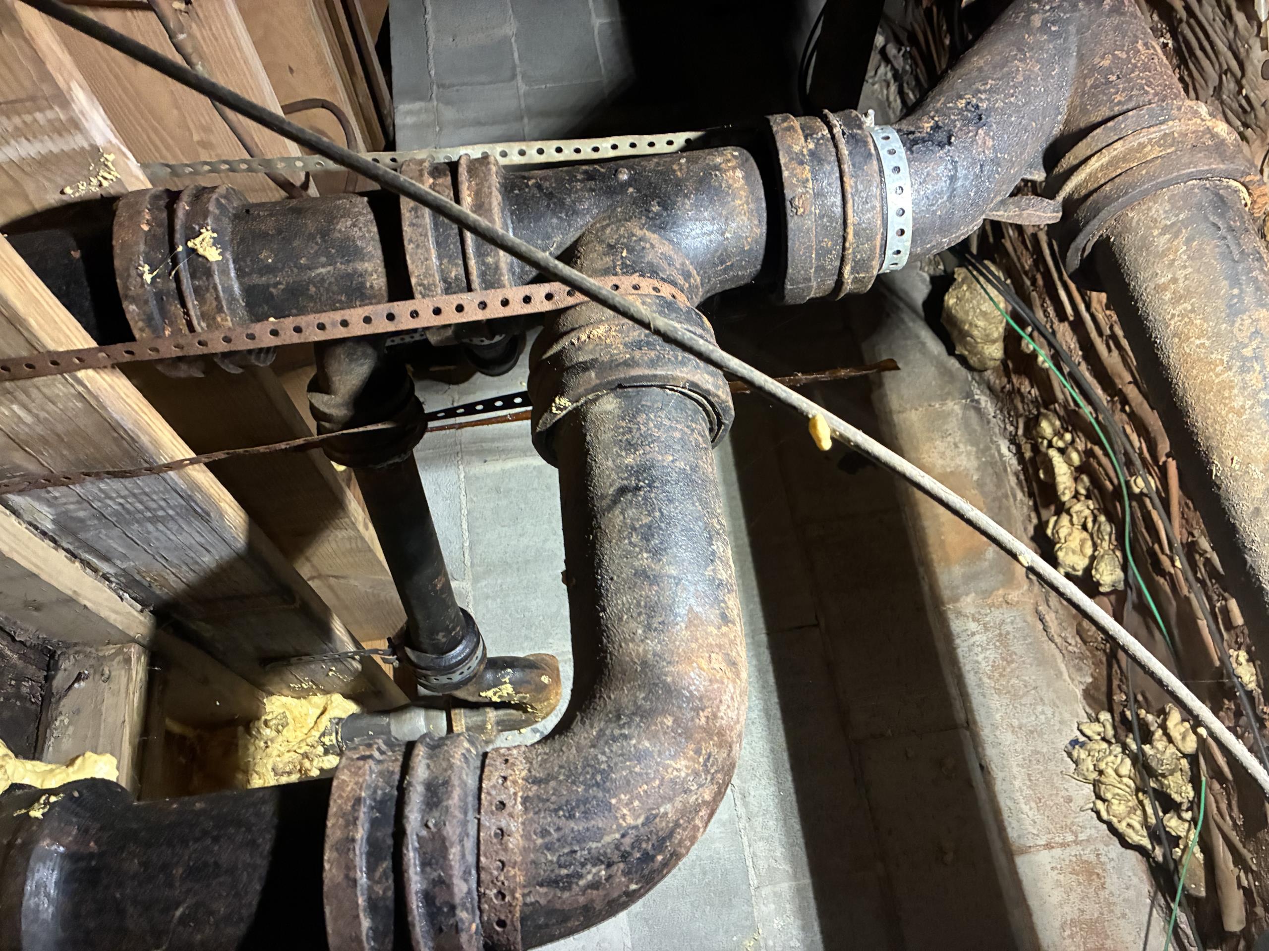 Call for sewer back up.

Arrived and met one tenant (Alex) Alex states that the sewer has backed up and the adjacent unit has the same problem. He showed me a video of sewage entering the crawlspace under the home.

I inspected both units and found symptoms consistent with main line backup.

Crawlspace inspection revealed sewage all over the floor in several spots from seepage and old sewer lines. The right side unit (As seen facing the house from the street) has had a wax ring failure and the subfloor is very damaged. Sewage has also spilled from here. 

Cast iron line exits the house, and it appears to be cast iron in the yard as well. I dug up a section in front yard to show me that at least a couple feet are cast iron here.

Due to the severely deteriorated state of the cast iron my recommendations were as follows: 

Absolute resolution: Replace cast iron sewer lines inside crawlspace, and in front yard

High priority task: Install cleanout to allow hydrojetting, jet line and camer