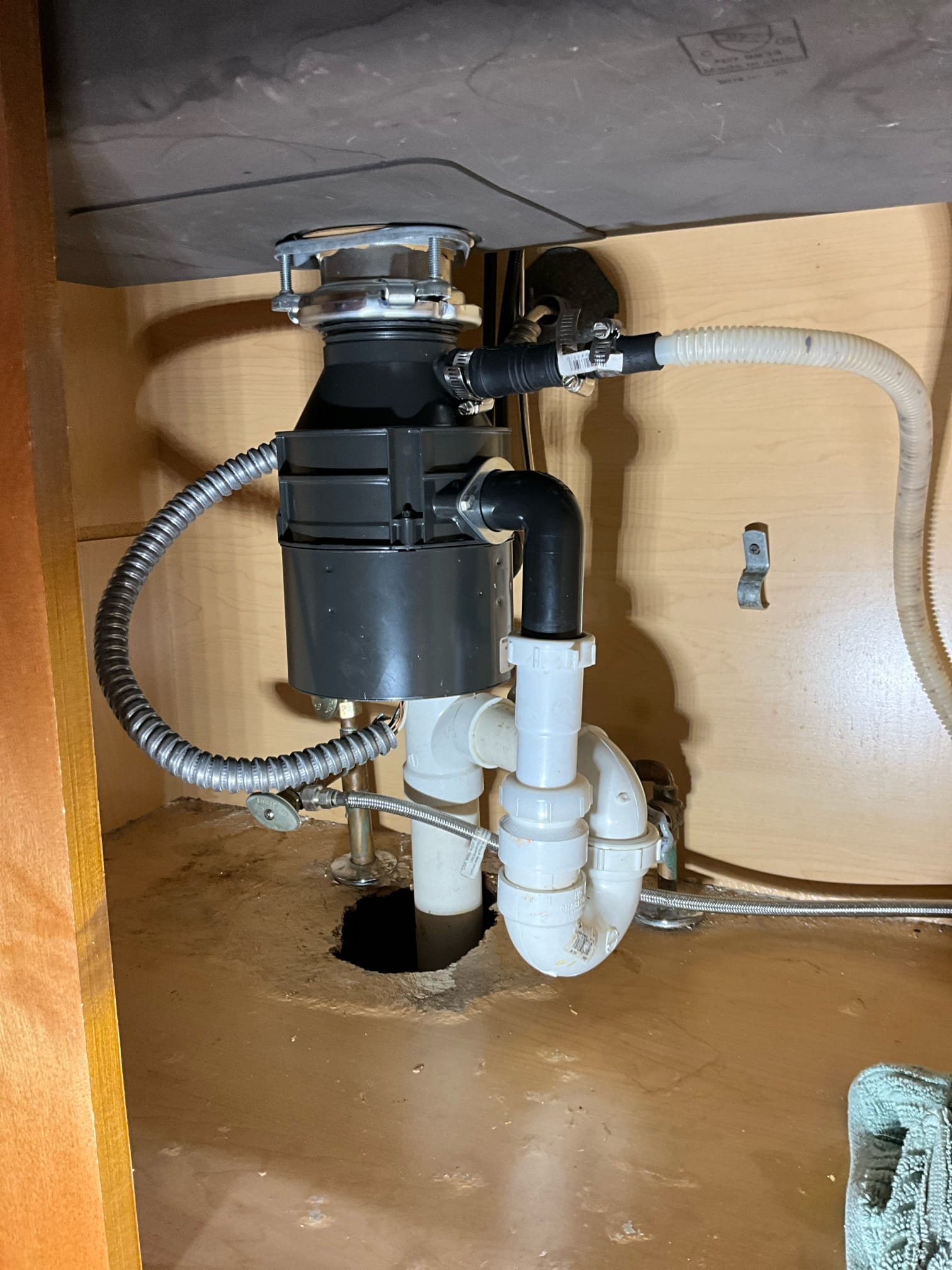 Call for leak under sink

Arrived and met with Anthony and Mrs. Smith. They stated that they noticed water in the garage and found a wet spot in the ceiling. After checking they found water under the kitchen sink.

Inspection findings:
Mr. And Mr.s Smith moved in to the home approximately 5-6 years ago. There was a kitchen remodel shortly before they purchased the house, but they are unsure of exact details. Home was built in 2002. I inspected under sink and found a single basin sink. With a new garbage disposal, with dishwasher drained in to disposal. Single trap, and vented via air admittance valve. I ran some water and found that the disposal has come loose from mounting bracket, and the lower trap nut was slightly loose. Seam around sink basin looks good, no separation or missing silicone. Air admittance valve may need to be replaced, as i noticed some hesitancy on drainage.20 year old shut off valves, multi turn style on copper pipes. Kraus single handle faucet. There is evidence 