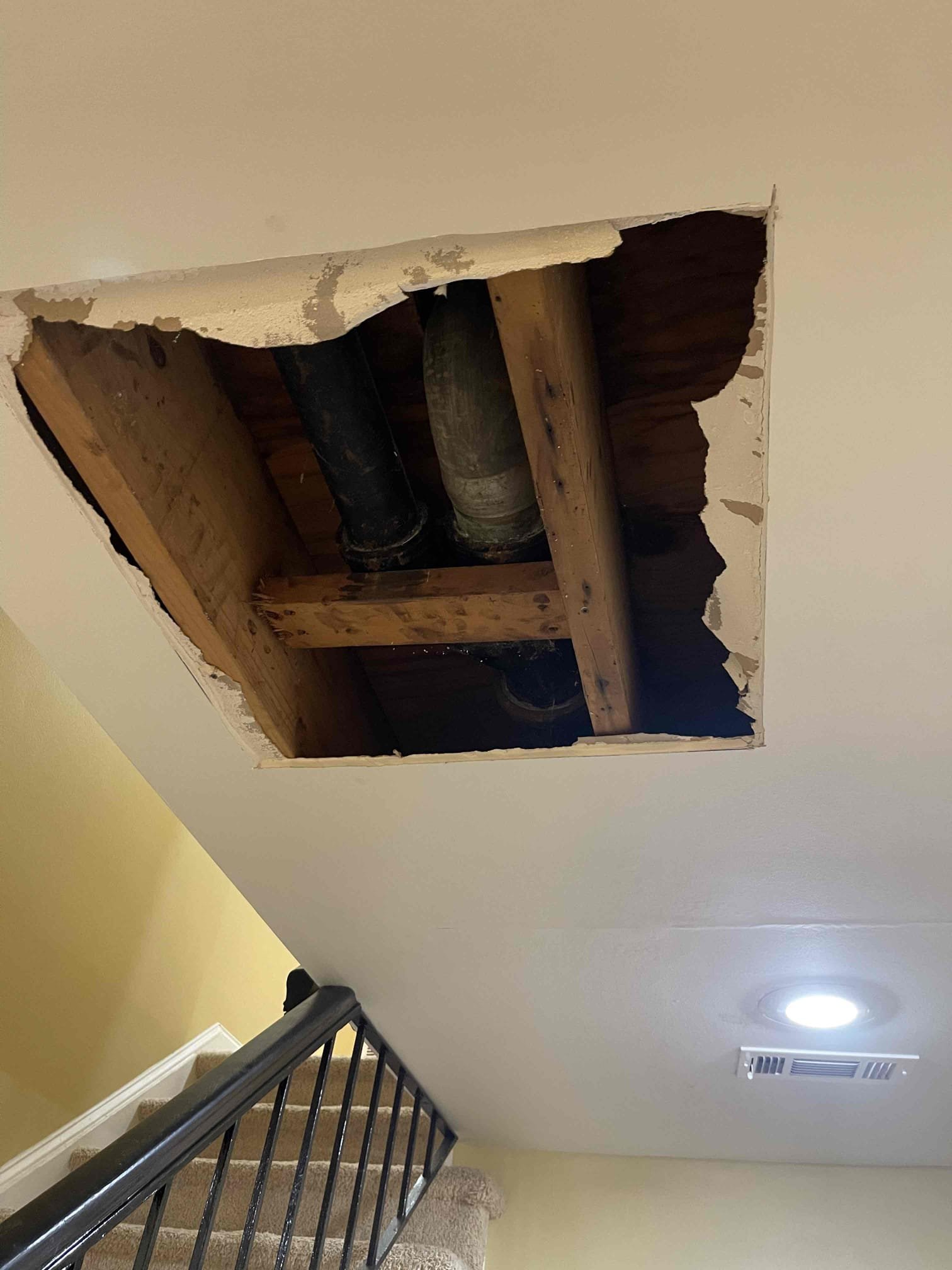 Came out for a leak in the ceiling. Arrived and met with homeowner. He directed me to the ceiling right in front of the front door. Signs of old water stains in the ceiling on the drywall. Customer said they had a back up in the past on that bathroom and had the blockage cleared and the toilet pulled and reset 1 year prior. Customer elected to open the ceiling so we could inspect for the source of the leak. After opening the ceiling we confirmed that the leak was coming from the seal on the bottom of the toilet by flushing toilet several times. We pulled the toilet and found the flange was sitting below the tile and the wax gasket was not touching the toilet. We had to resort to installing an extra thick wax ring to form a proper seal as we are unable to replace the flange without significant cast iron replacement in the ceiling due to the homes builders use a lead bend of the flange with a very short sweep that will not allow modern pvc sittings to fit inside the same amount of space.
