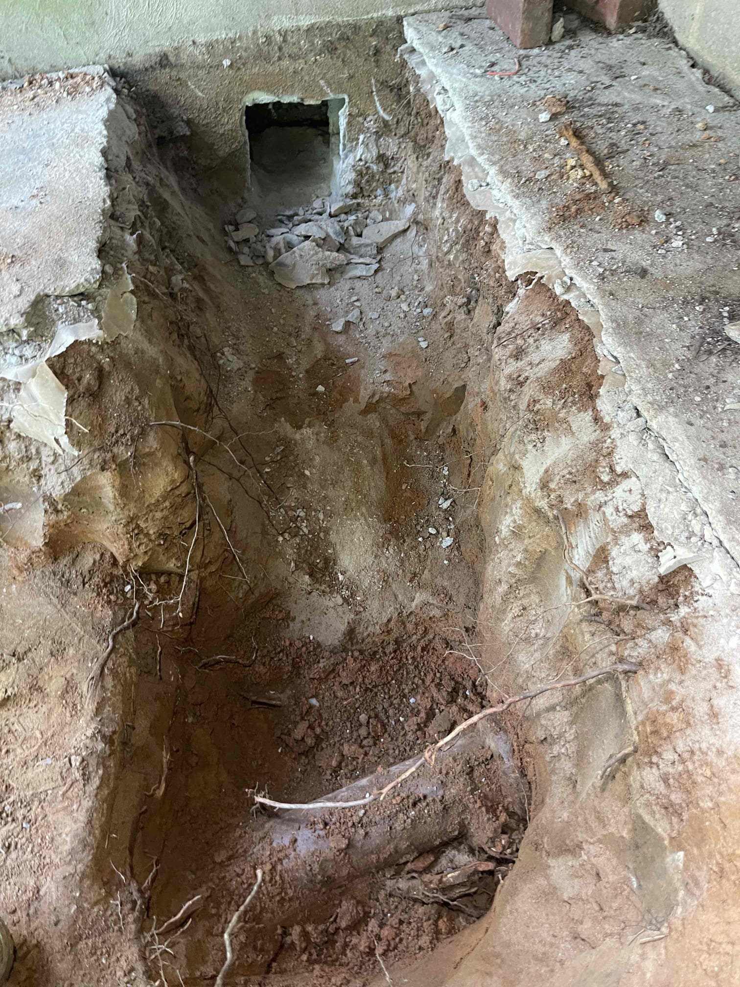 Came out for a sewage back up. Whole house was backing up and sewage was very very slow to drain. Was backing up into the bath tub. Homeowner recently had her septic tank pumped so we knew it was not that. Received approval to pull the toilet and snake/camera the line. Pulled toilet, snaked blockage and got it to drain, ran the camera and found there was a section of cast iron under the concrete patio outside that was heavily rotted and broken as it went into the septic tank. Pipe was full of roots. We received approval to reroute the line. Jack hammered the concrete under the back deck and dug down to the septic tank. Trenched over to the crawlspace and made a new penetration through the wall. Routed 20’ of 4” pvc through the crawlspace, and an additional 8’ down into the septic tank. Climbed into the septic tank and removed the old rotted baffle tee from inside and replaced with pvc. Resealed the penetration with hydraulic cement. Installed two way cleanout outside for future servici