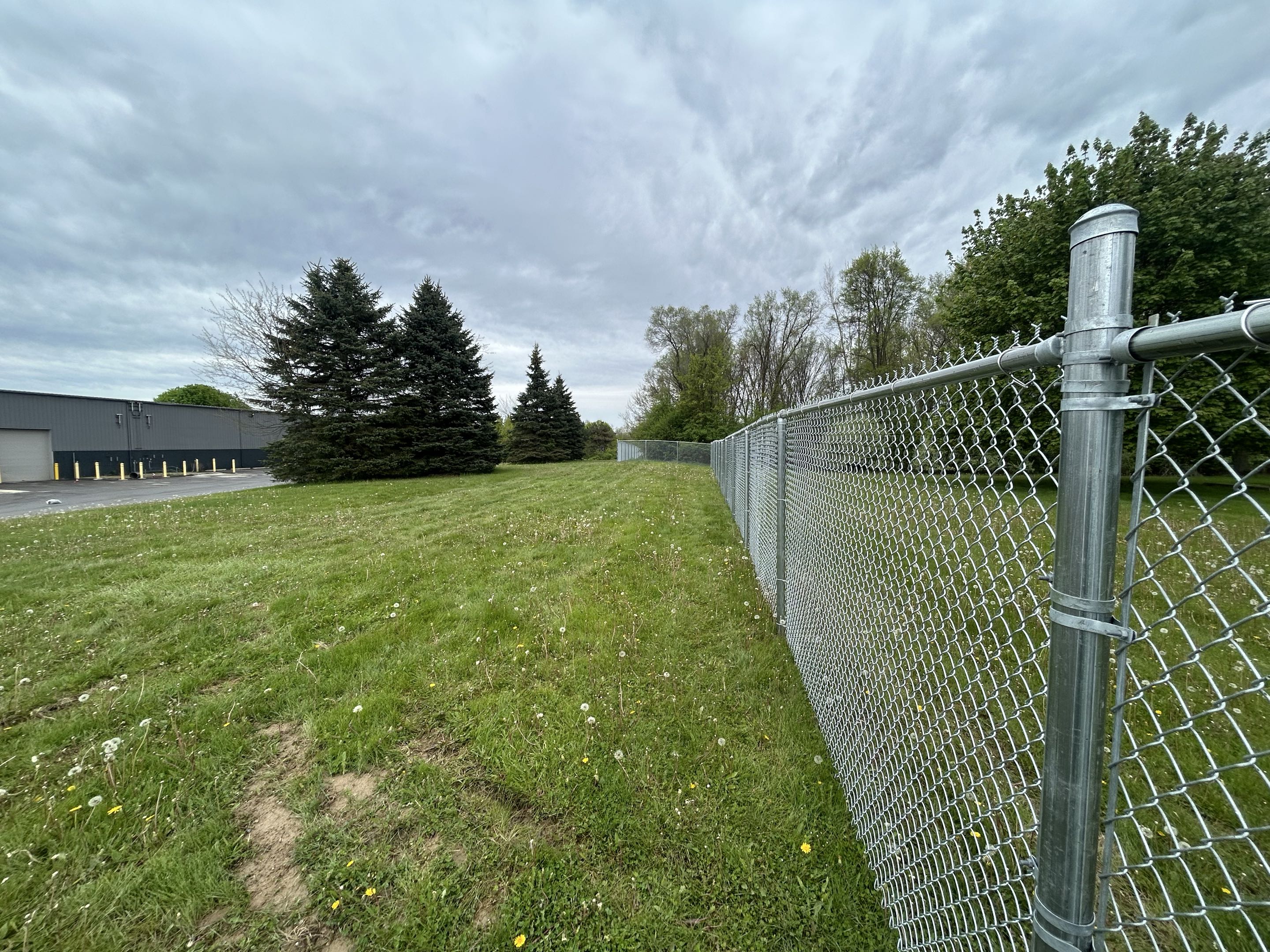 Ypsilanti, MI - Top Rail Fence finished this chain link commercial fence in Ypsilanti.  It adds security by better utilizing the cantilever gate and now encompasses the entire campus opening up flow between the two buildings.