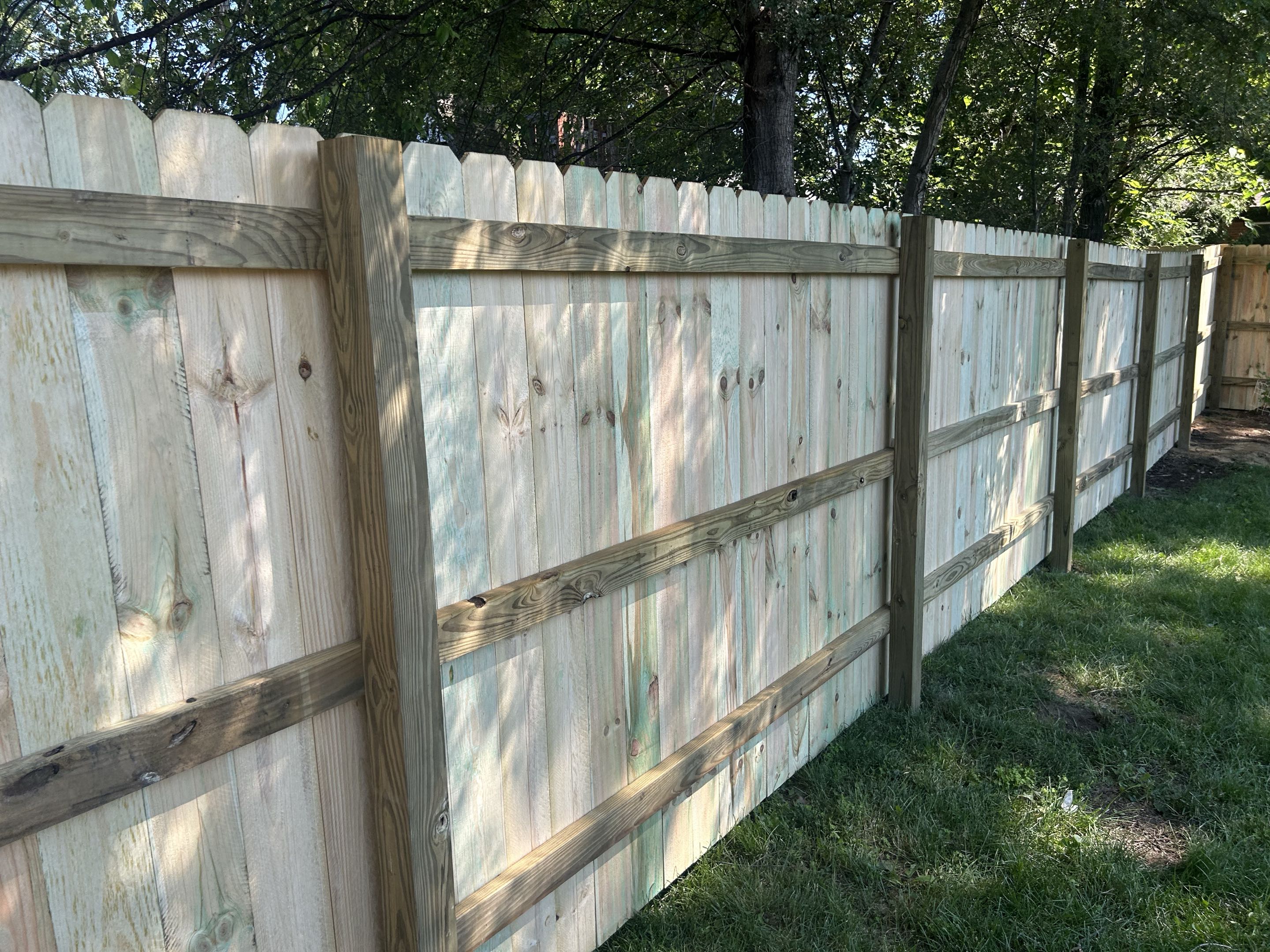 Ypsilanti, MI - Top Rail Fence Ann Arbor in Ypsilanti Township installing a classic treated pine dog ear picket fence.  It looks great naturally but treating it with stain and sealant will help it last much longer and endure the elements.