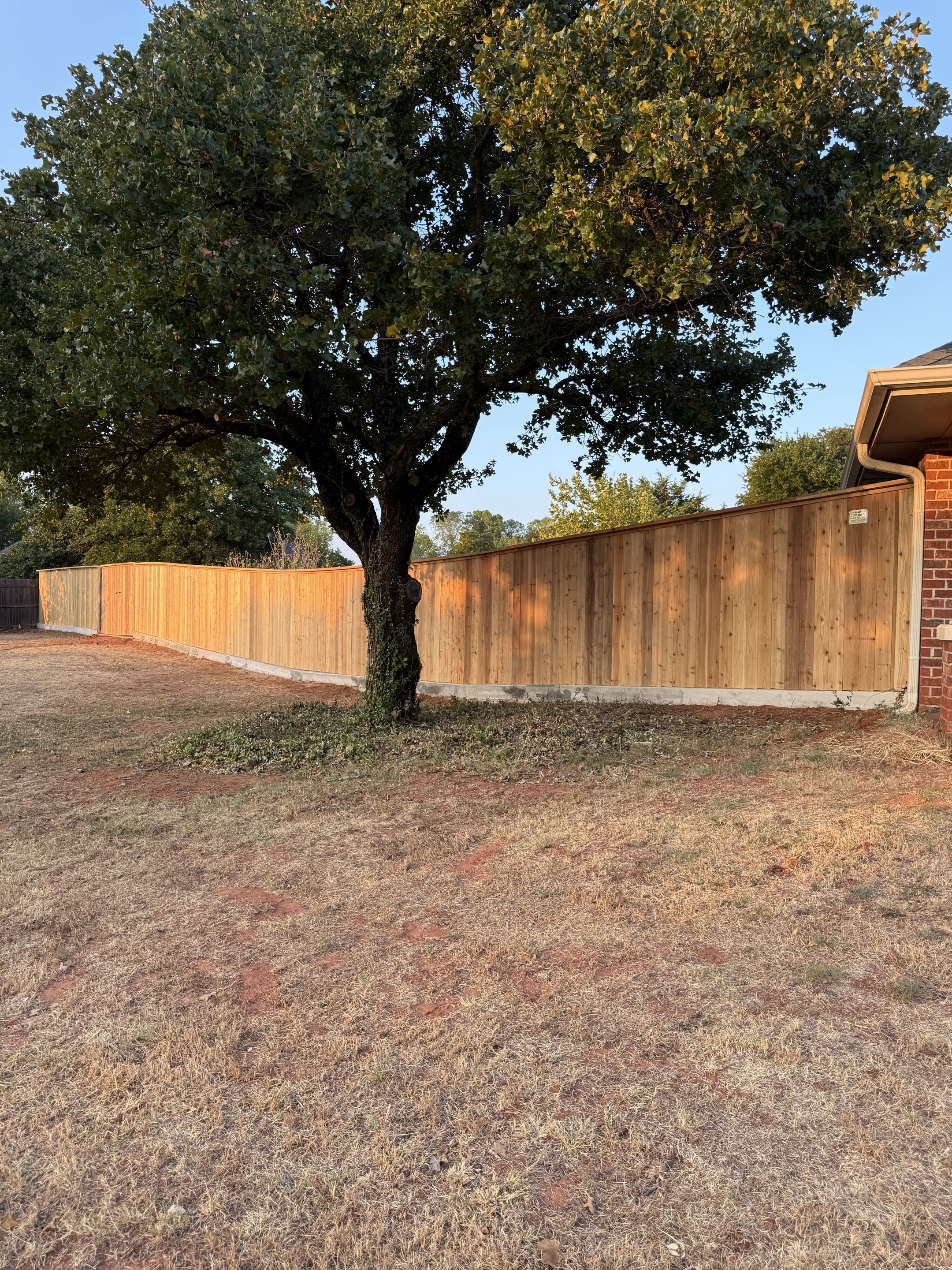Blanchard, OK - This Japanese cedar cap and trim fence was built to look great and stand the test of time. The concrete footer gives the homeowner that extra layer of security they needed to finally stop their dogs from digging out. It turned out absolutely beautiful, adding a clean, finished look to the yard while giving the homeowner peace of mind without the constant worry.