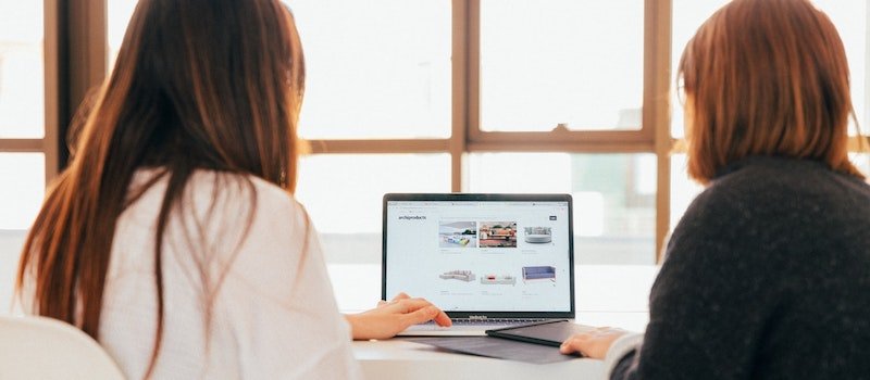 Two women look at computer screen