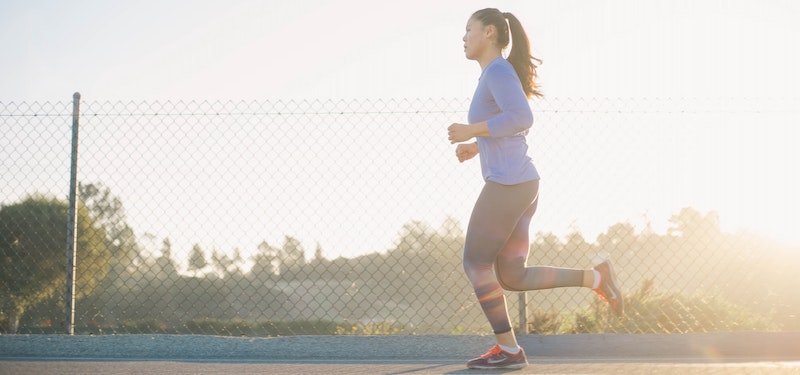 Woman running on track at sundown