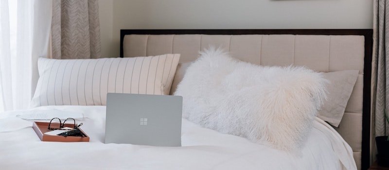 Windows computer on bed next to glasses