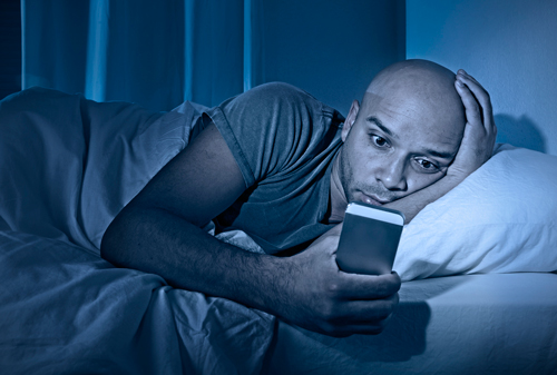 muž v posteli závislý na telefonu