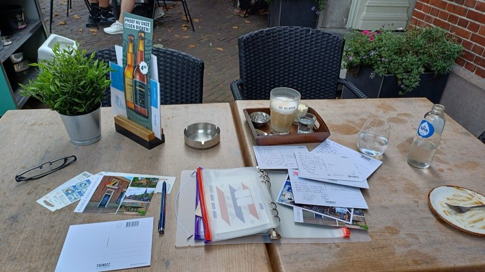 Spread of Baarle-themed postcards and Dutch priority stamps laid out on a wooden table