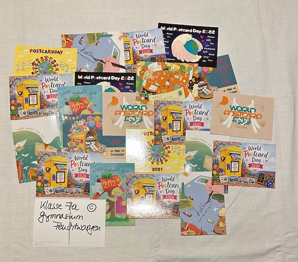 People gathered around tables at a World Postcard Day activity, writing and colouring postcards together.