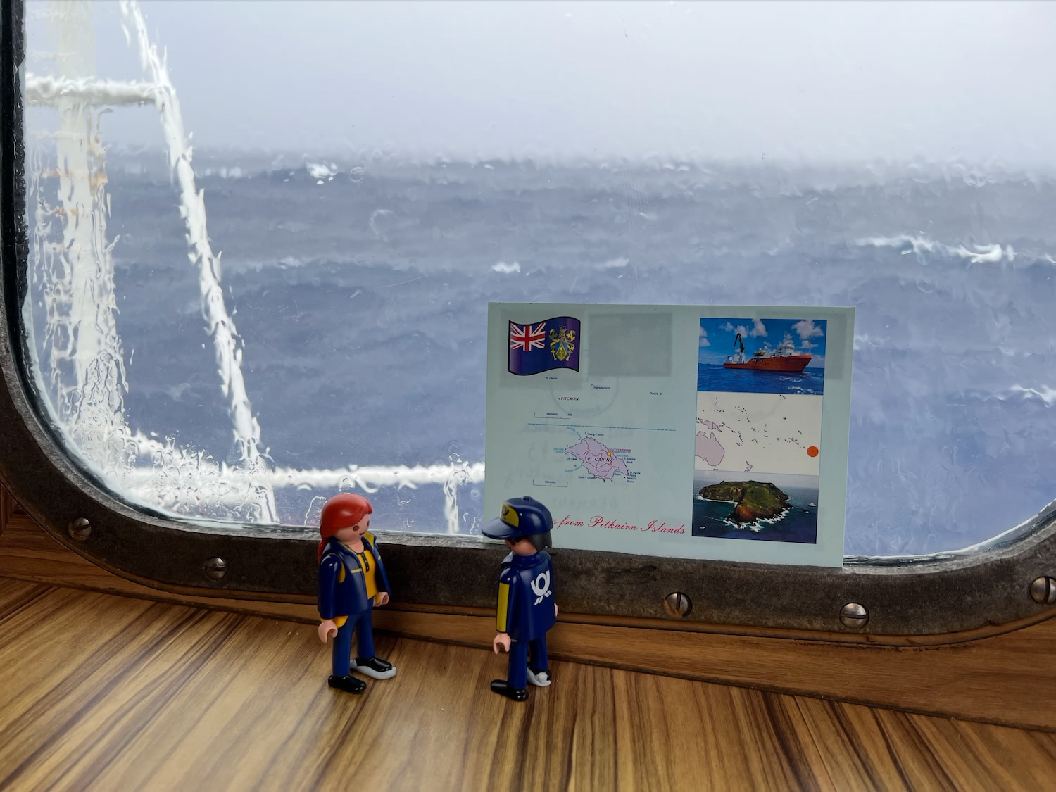 The Little Mail Carriers standing by a ship's window, looking out over the Pacific Ocean.