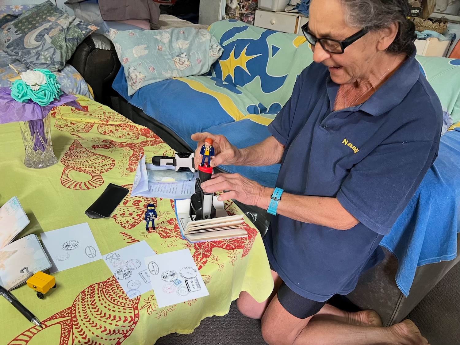 A man surrounded by postcards and postal supplies at a table on Pitcairn Island.