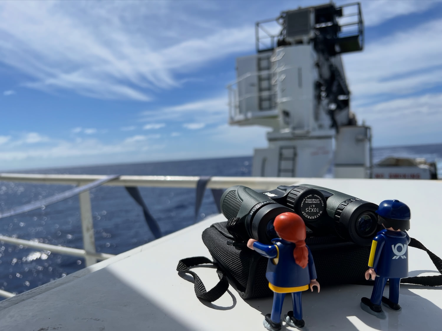 The Little Mail Carriers standing aboard the ship with the ocean and ship's equipment behind them.