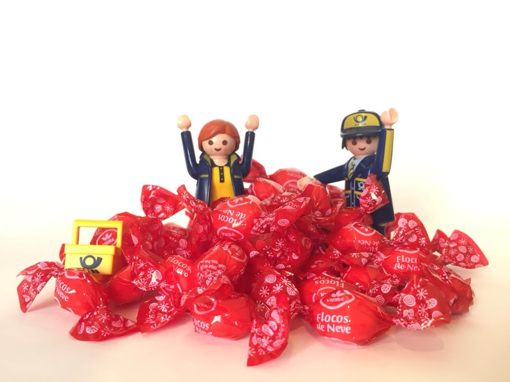 Two toy mail carriers sit among a pile of sweets