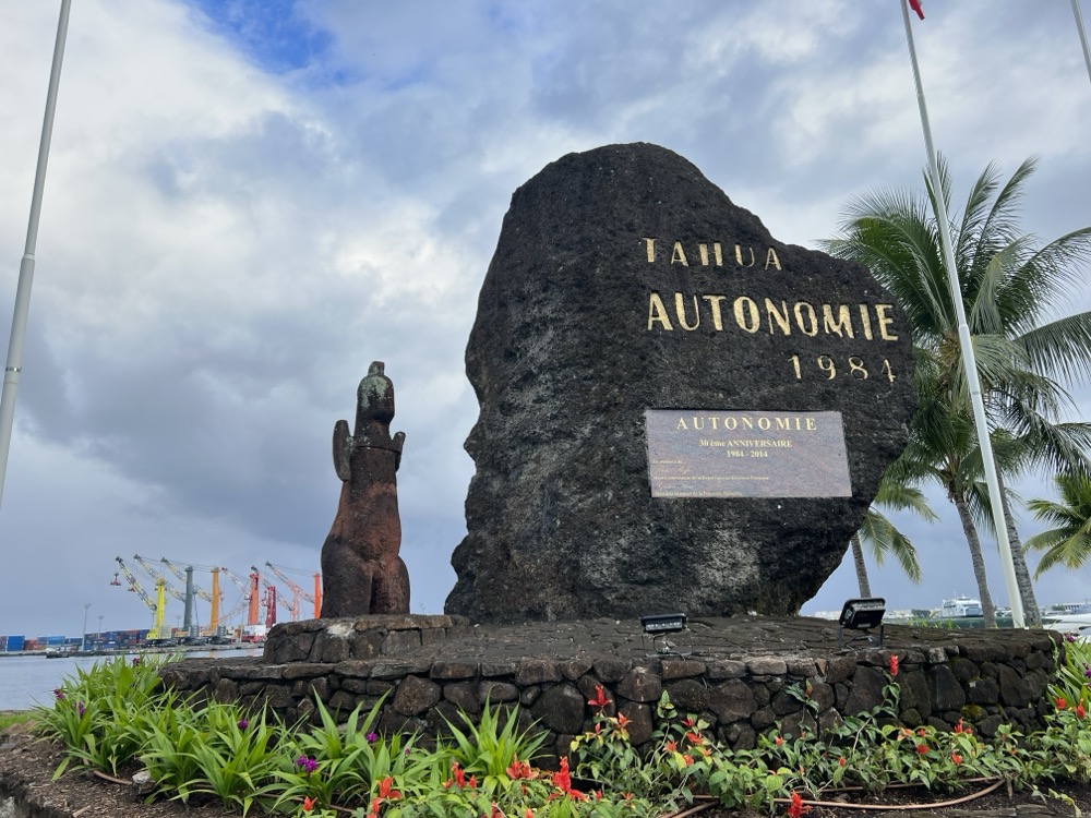 Monument in Papeete commemorating French Polynesia’s autonomy, with a large dark stone marked “Tahua Autonomie 1984” beside the harbour.