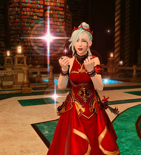 A screenshot from Final Fantasy XIV. A character with white hair in a high ponytail, wearing a red dress with gold embellishments and a red tiara, is surrounded by sparkles and has a look of wonder on their face. Behind them, you can see a library with floor to ceiling books.