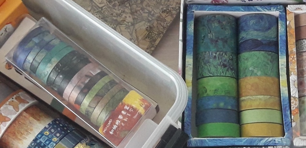 Two sets of Van Gogh-themed washi tape rolls, including a narrow tape set in a plastic box and wider rolls in a cardboard box.