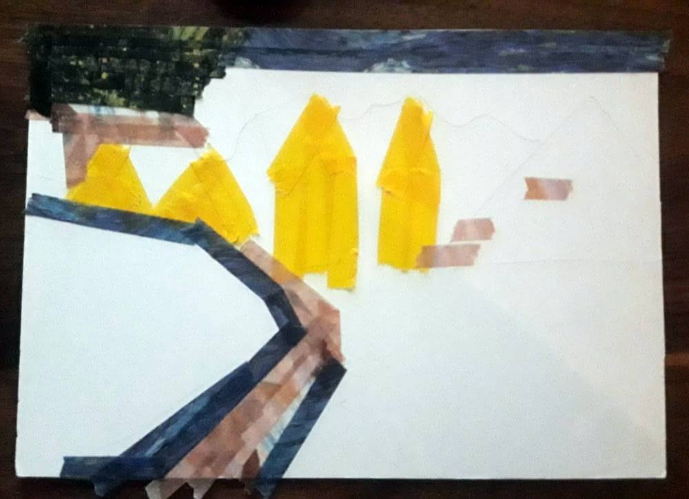Second step of a washi tape postcard, with yellow houses and some darker roof and path areas filled in.