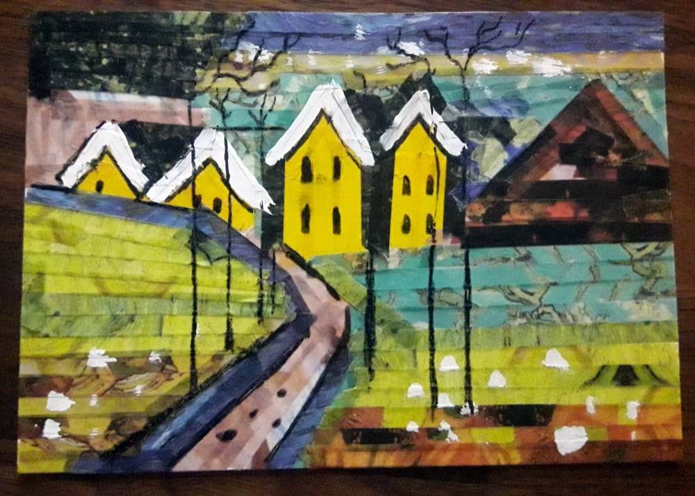 Finished handmade washi tape postcard showing a colourful winter landscape with yellow houses, snowy roofs, trees, hills and a path.