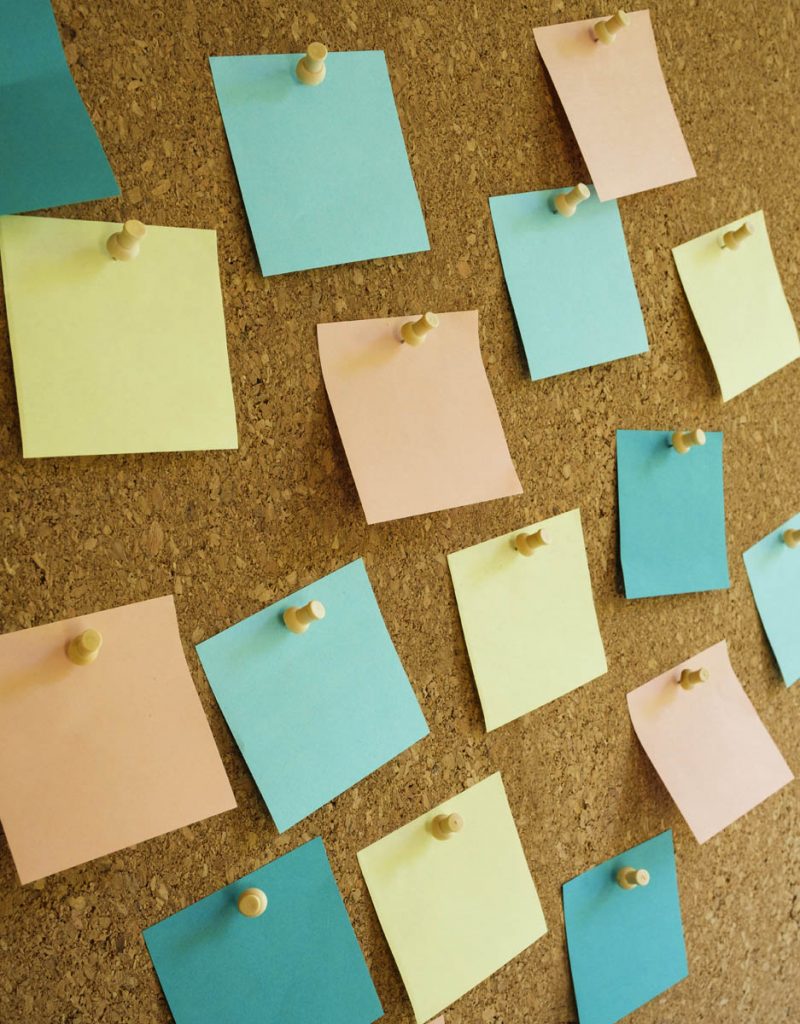 Closeup of multi colored post it notes on bulletin board