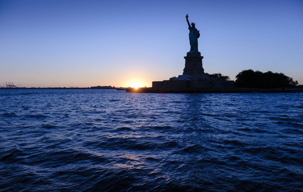 Statue of liberty amidst hudson river during sunset StockFreedom
