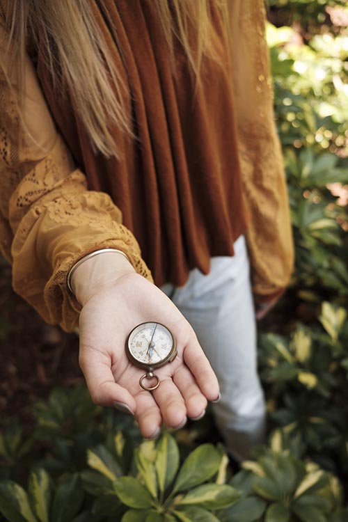 Woman's hand holding a compass in the woods StockFreedom Premium