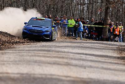 Spectators watch as Travis Pastrana and Rhianon Gelsomino race through the forest.