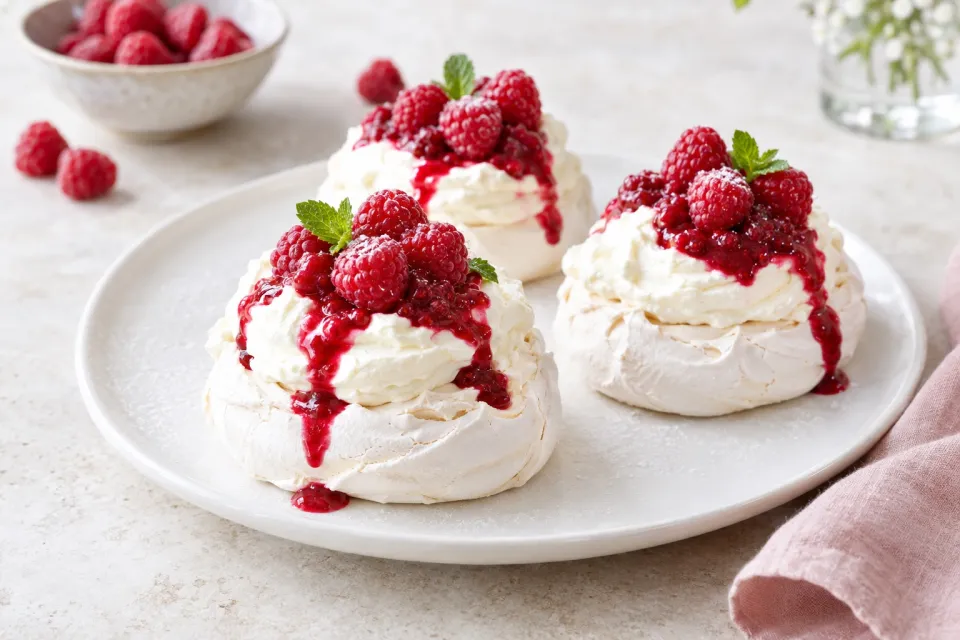 Individual Pavlovas with Cream Cheese Whipped Cream and Raspberry Sauce