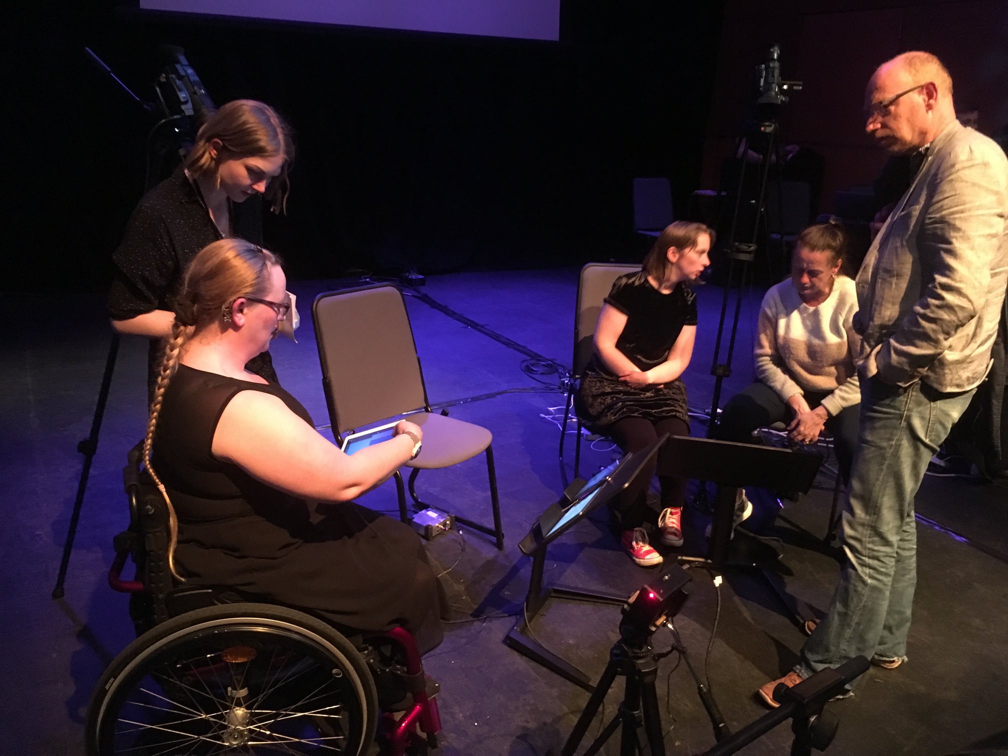 Several musicians are engaged in an ensemble rehearsal holding iPads