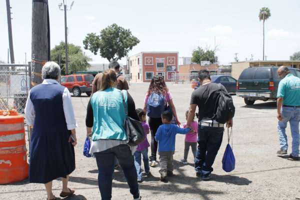 Sister Norma Pimentel (far left) and volunteers walk with migrants who just finished stopping by Catholic Charities for assistance.
