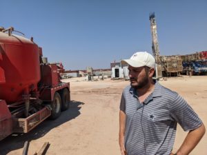 A man outside near oil well machinery.