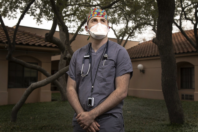 geriatrician Dr. Michael Krol in front of a building and trees wewaring scrubs and a face mask