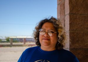 a woman with curly hair and glasses standing next to a building