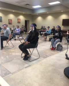 people waiting in spaced out chairs and face shield during jury selection