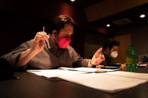 a man sitting at a desk wearing a red mask