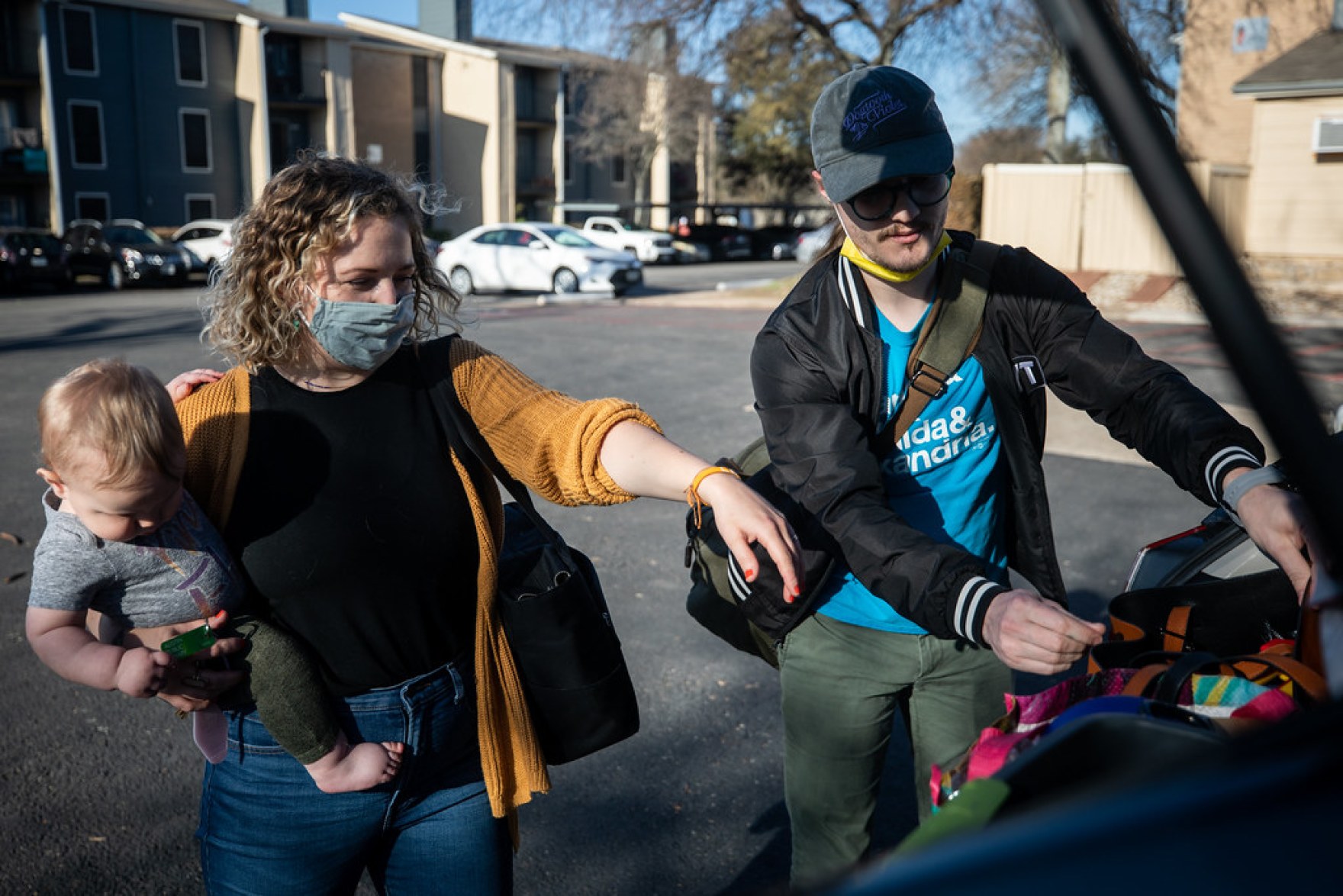 a couple with a baby getting stuff out of the trunk of their car