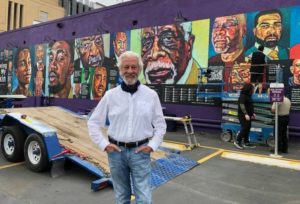 a man standing in front of a mural he painted
