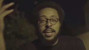 a man singing, wearing glasses