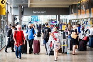 a crowd of people moving through an airport checkpoint