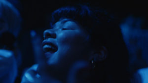 a blue light shines on a smiling Doris Mu&ntilde;oz in the film "Mija"