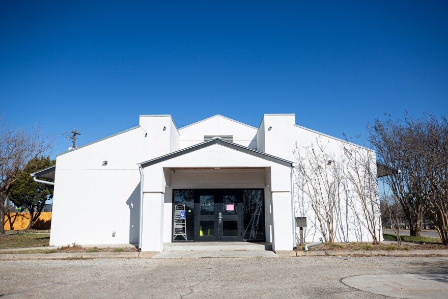 a white building with trees on each side that serves as a health care clinic