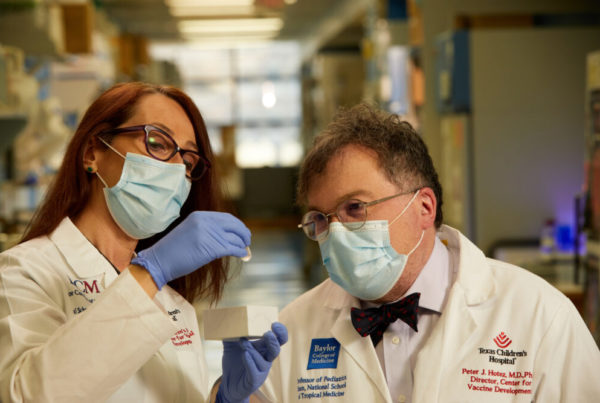 two doctors wearing face masks and looking at a vaccine vial