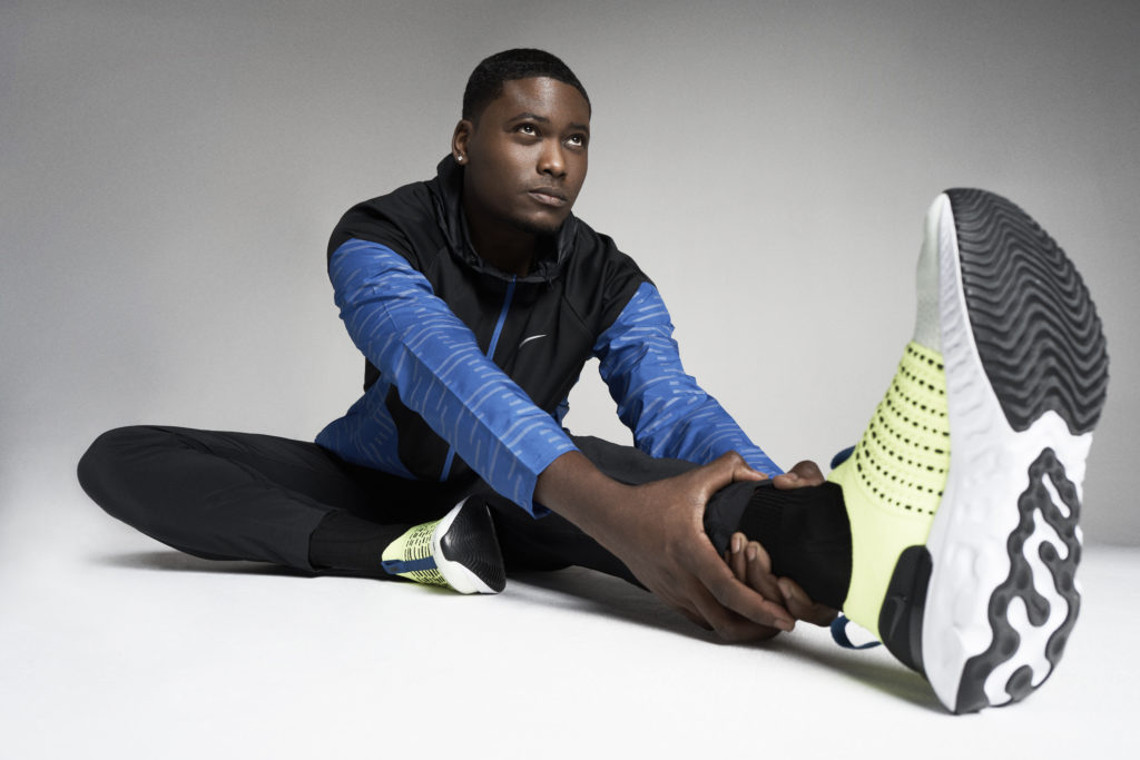 a young man wearing athletic gear stretches in a sitting position with one leg in front of him