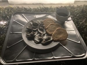 a plate of oysters and cookies with a cup of coffee nearby